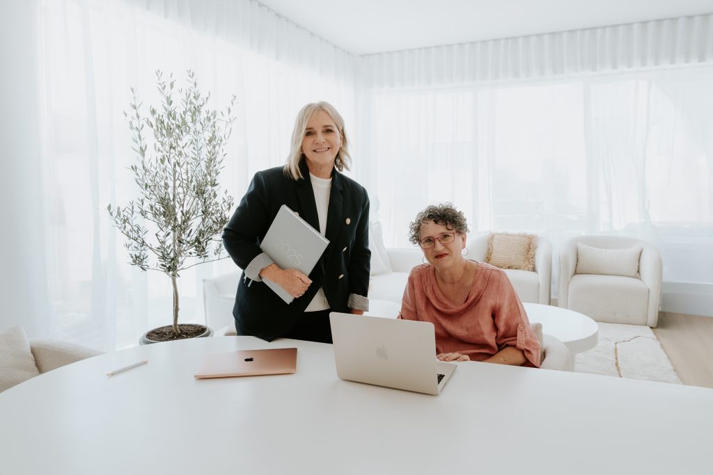 Jenn and Marlène working at a table with a laptop open in front of them.